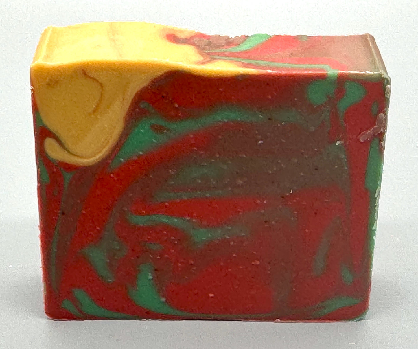 Handmade tallow soap with red, green, and gold swirls, scented with apple, orange, peppermint, and clove fragrance-front view