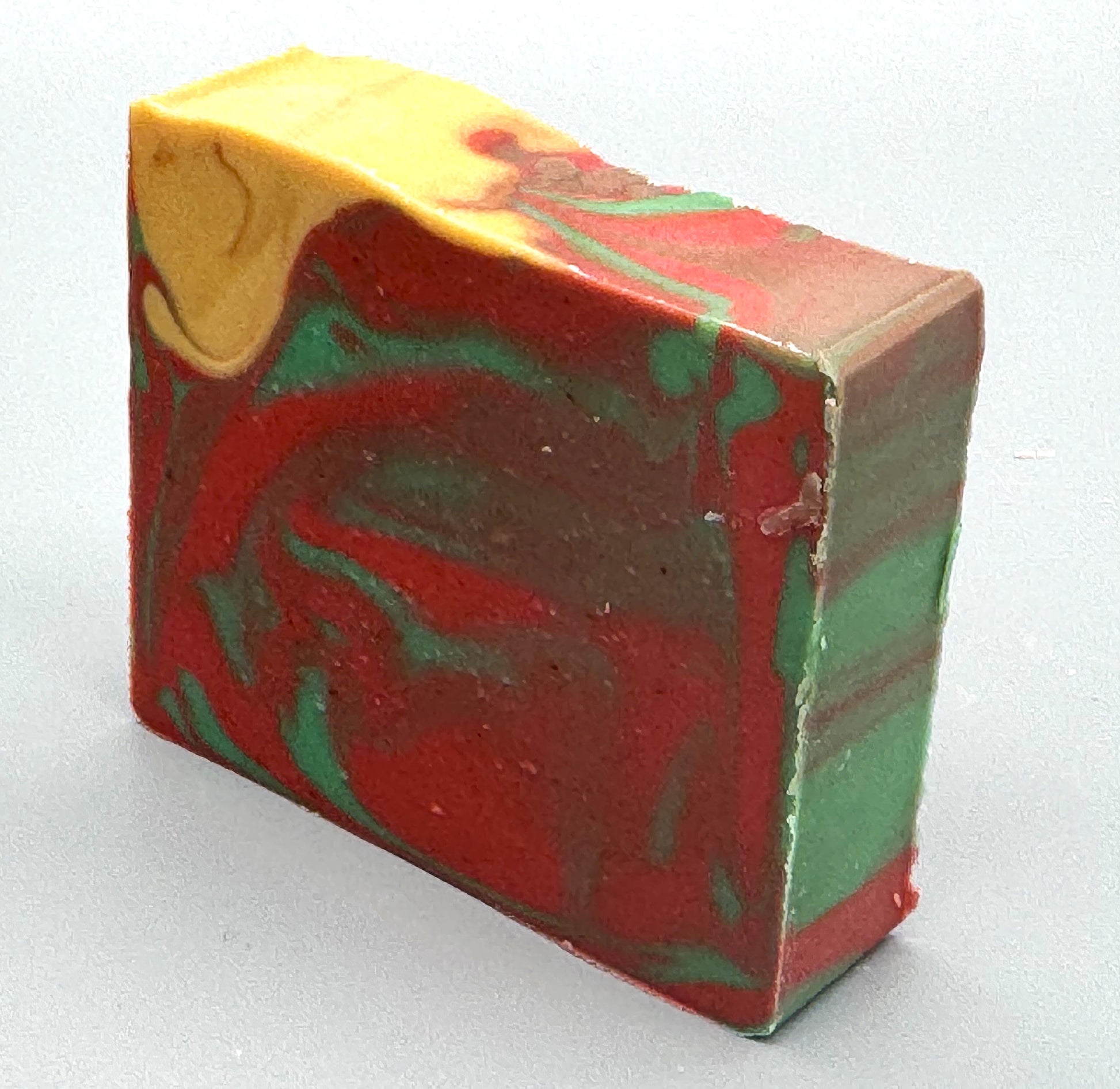 Handmade tallow soap with red, green, and gold swirls, scented with apple, orange, peppermint, and clove fragrance-left view