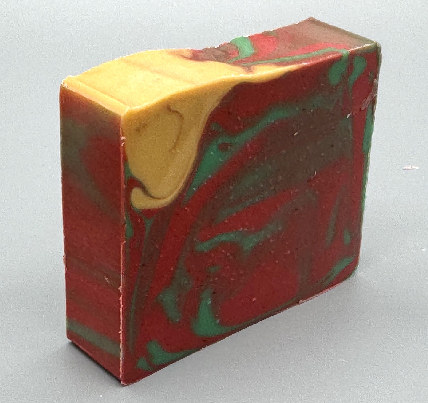 Handmade tallow soap with red, green, and gold swirls, scented with apple, orange, peppermint, and clove fragrance-right view
