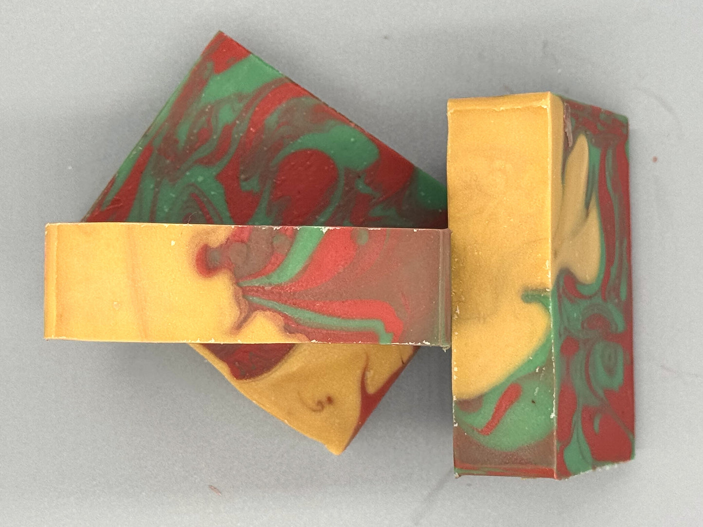 Handmade tallow soap with red, green, and gold swirls, scented with apple, orange, peppermint, and clove fragrance-3 bar top view
